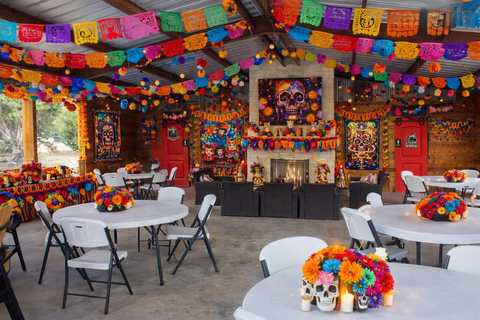 Al's Hideaway pavilion decorated for Dia de los Muertos with papel picado banners, marigolds, and a community ofrenda altar